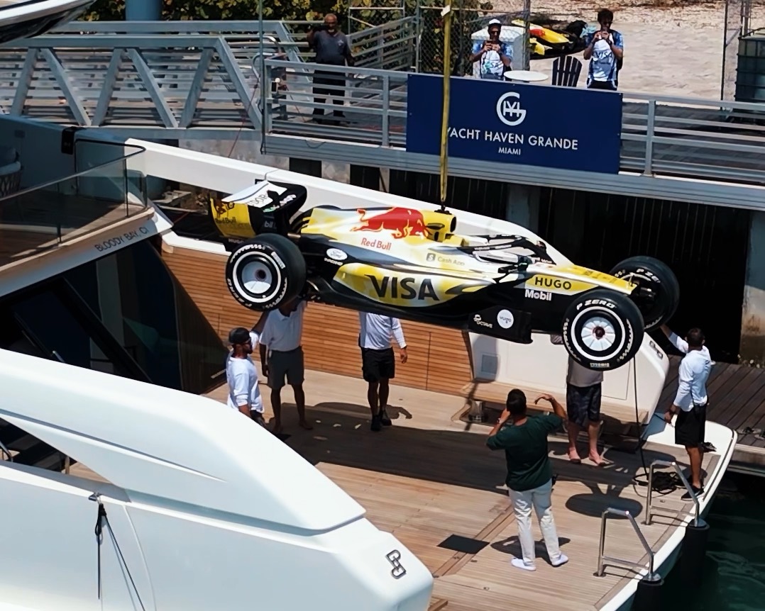 A Formula 1 car lowered by crane onto the deck of a Maritime yacht in Miami